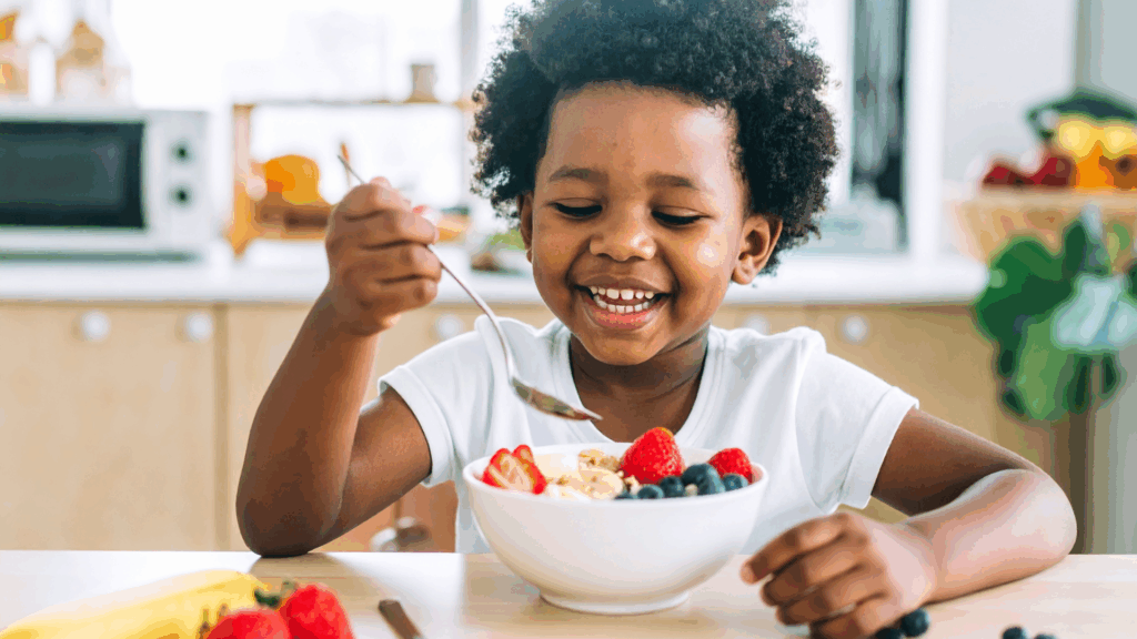Happy kid eating oatmeal with fruit picked from the family garden. Healthy soil grows fruit and veggies that taste better and are healthier for your family.